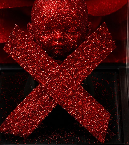 Close-up of the red glittered Star Crossed Love Affair ME Doll™ head and X shaped design inside a clear acrylic display case.