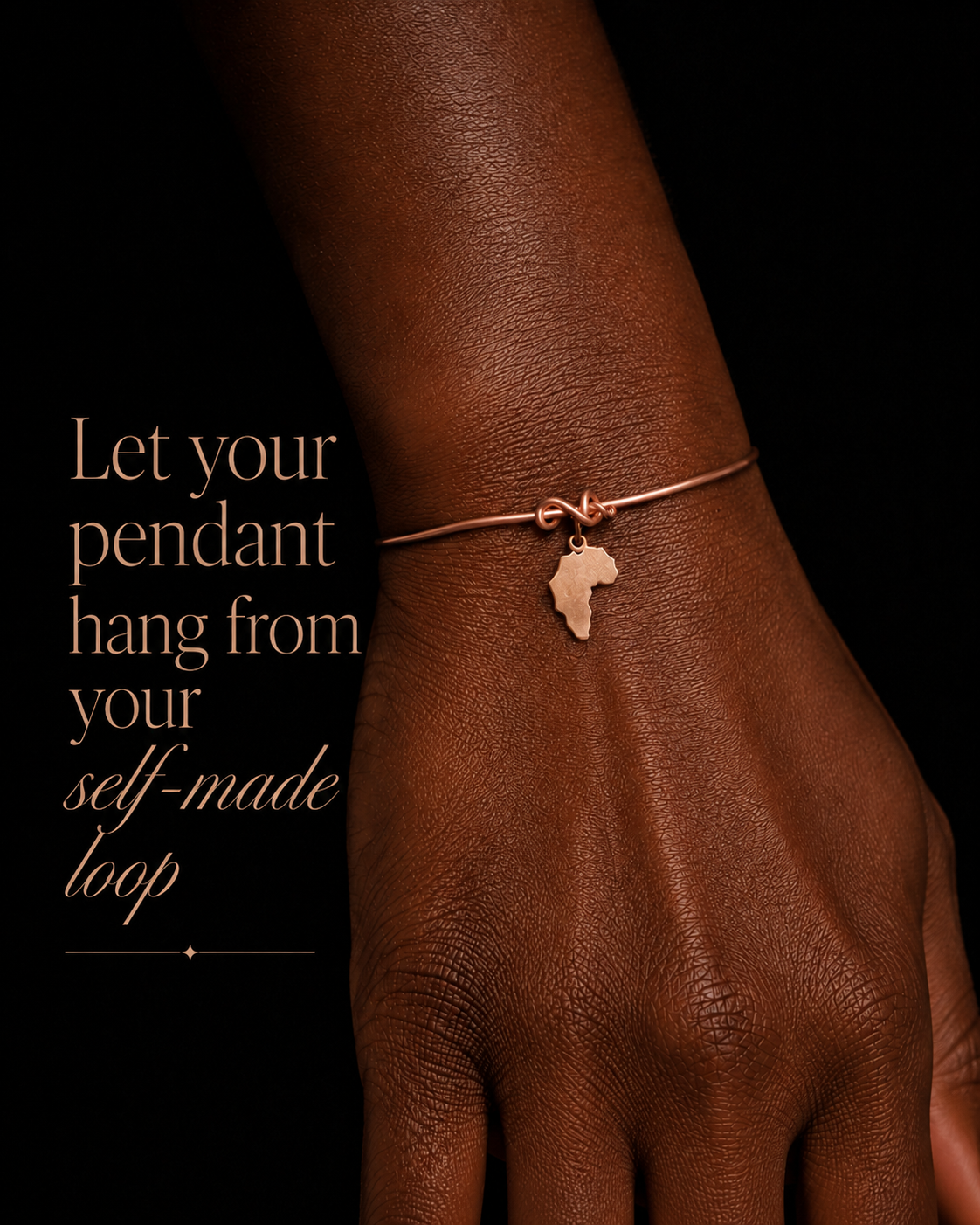 Close-up of the Melanin Copper Cuff with a gold-plated map of Africa charm hanging from a wire loop on a dark-skinned wrist.