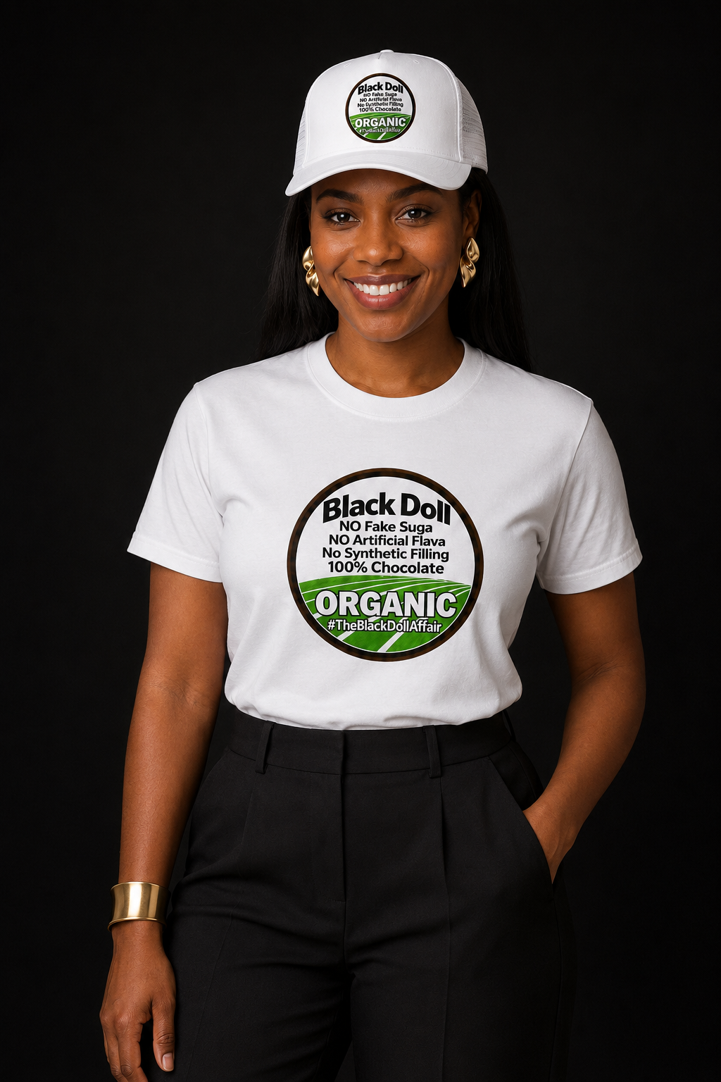 A woman modeling The Black Doll Affair's 'Organic Original' T-shirt and matching five panel white trucker-style baseball cap with a flat brim, mesh back panels, and a circular front patch reading 'Black Doll' No fake suga, no artificial flava, no synthetic filling, 100% chocolate.' 'ORGANIC' on a black background.