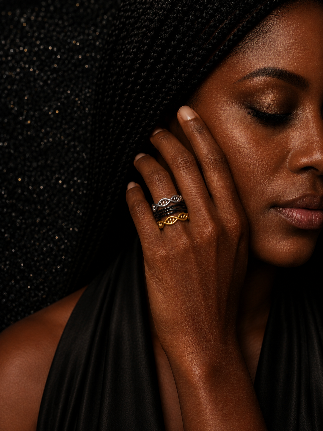 A close-up lifestyle shot of a woman wearing the Unity Helix Rings™ stacked together in black, silver, and gold. The Black featuring a forever loop and the gold and silver featuring the double-helix design.